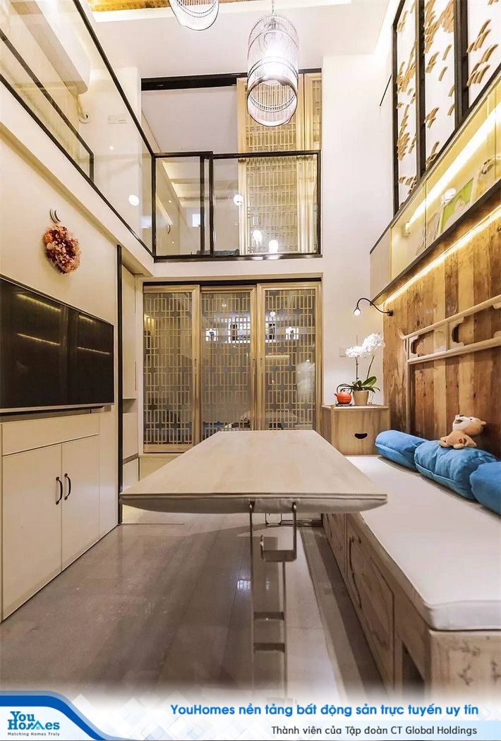 Phòng khách nhỏ gọn với ghế ngồi sát tường, bàn điều chỉnh độ cao và kệ đựng đồ đặt song song.