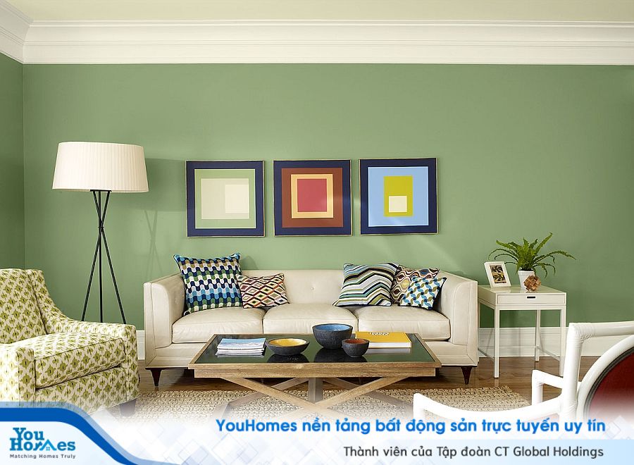 Tường màu xanh với những chi tiết trang trí giúp phòng khách có vẻ ngoài ấn tượng. Sofa và gối họa tiết là điểm nhấn cực thú vị, phá tan cảm giác "một màu".